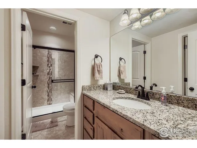 a bathroom with a granite countertop sink a mirror and shower