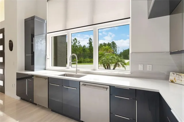 a sink with a large window and cabinets