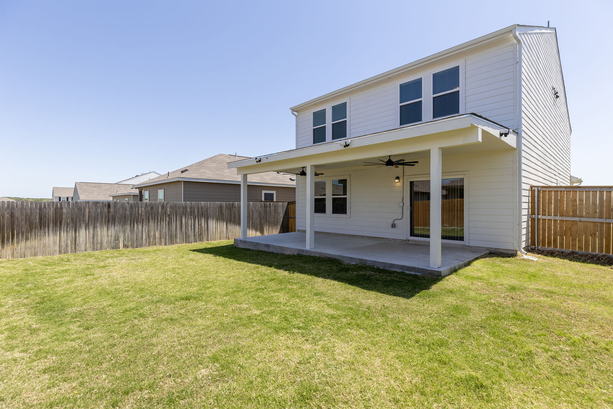 409 Line Of Fire Way Jarrell, TX 76537 - Photo 30 of 30 Expansive backyard featuring a covered patio, ceiling fan, outdoor lighting, full wood privacy fence, and open lawn space.