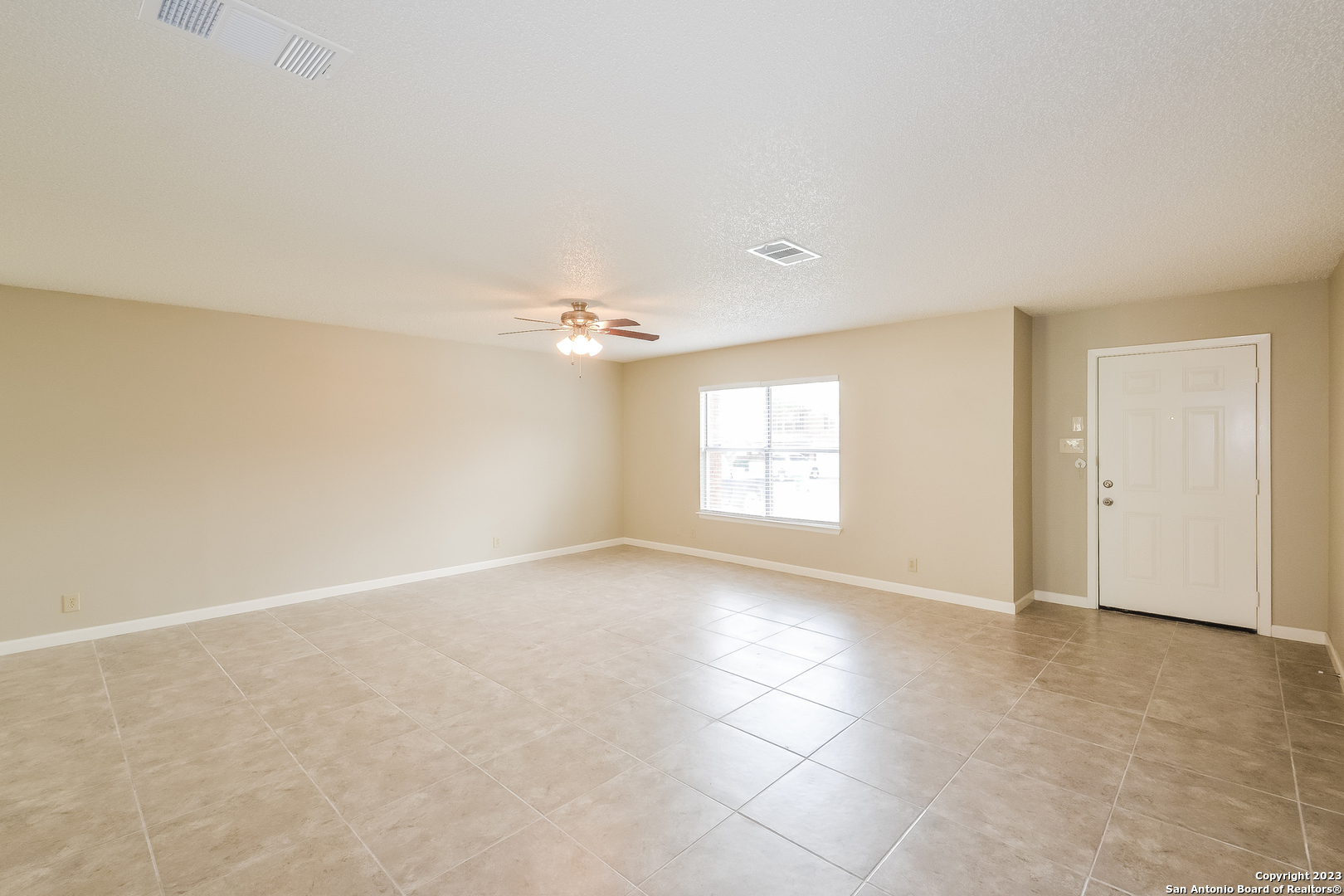 8007 Manderly Place Converse, TX 78109 - Photo 2 of 15 an empty room with windows and chandelier fan