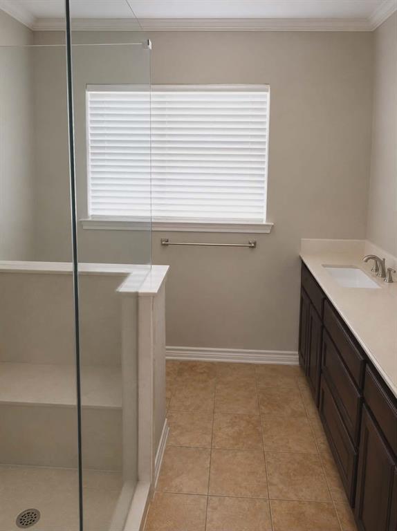 14752 Ranch Road Forney, TX 75126 - Photo 21 of 40 Bathroom featuring a glass-enclosed shower with integrated shelving, a dark wood-finish vanity with an undermount sink, a light-toned countertop, and tiled flooring-This photo was taken before family moved in