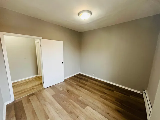 an empty room with wooden floor and entrance