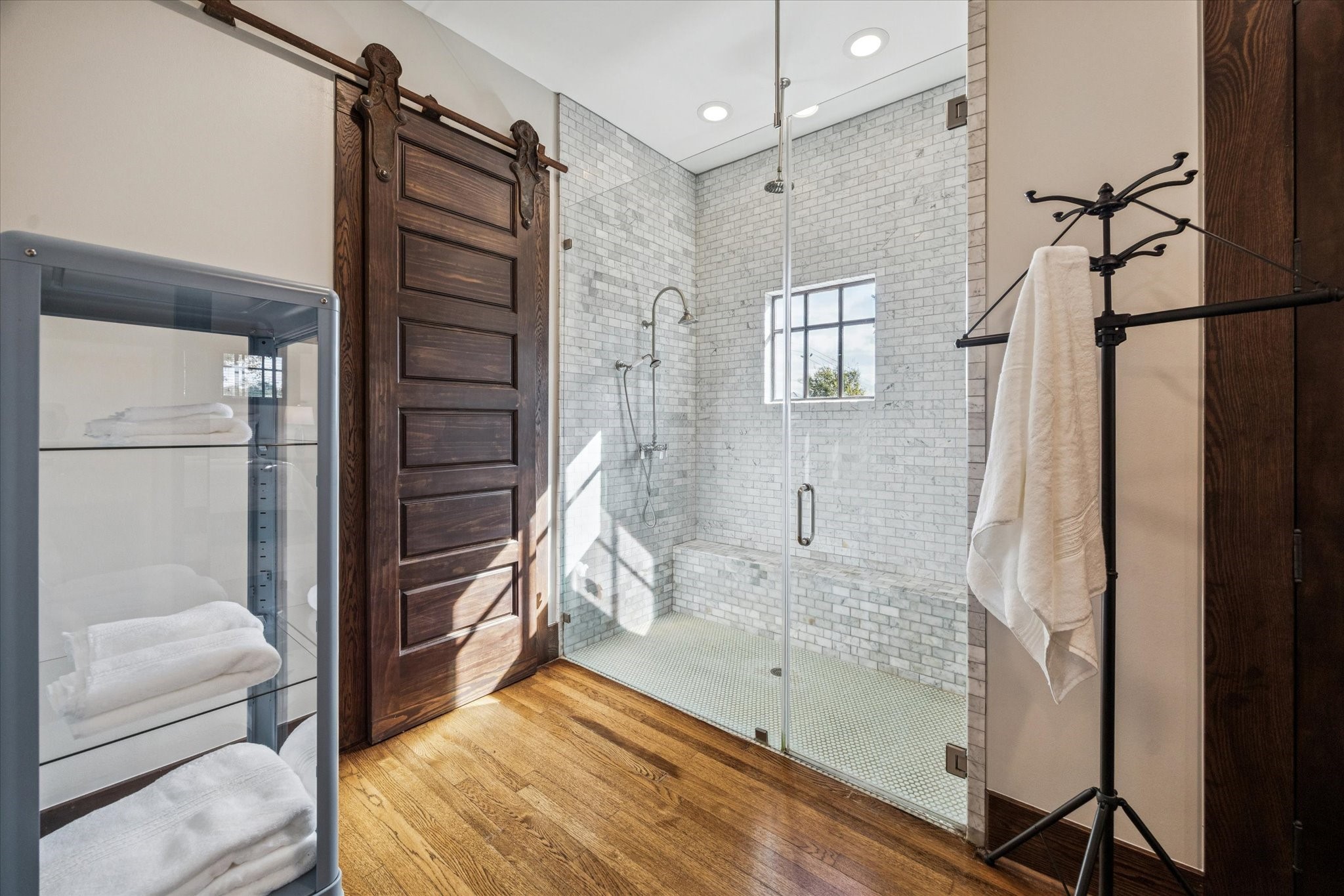 512 Archer Street Houston, TX 77009 - Photo 23 of 40 Impressive glass-enclosed shower featuring a marble tile surround, bench, dual shower heads including a rain shower, and a classic penny tile floor.