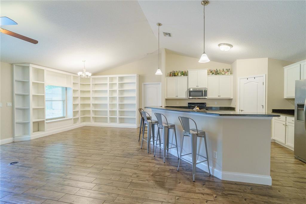 5273 Southwest 96th Place Ocala, FL 34476 - Photo 16 of 55 a view of kitchen with granite countertop a stove a sink a refrigerator and white cabinets with wooden floor