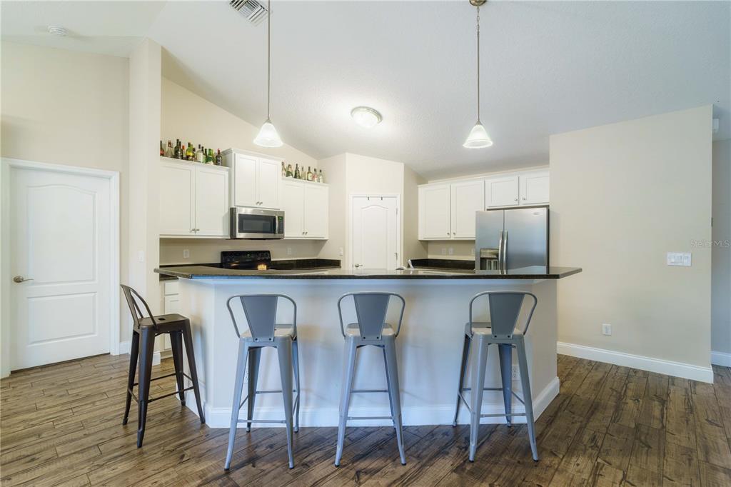 5273 Southwest 96th Place Ocala, FL 34476 - Photo 17 of 55 a kitchen with stainless steel appliances granite countertop a dining table chairs refrigerator and microwave