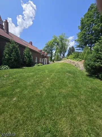 a view of a big yard with flower plants and large trees