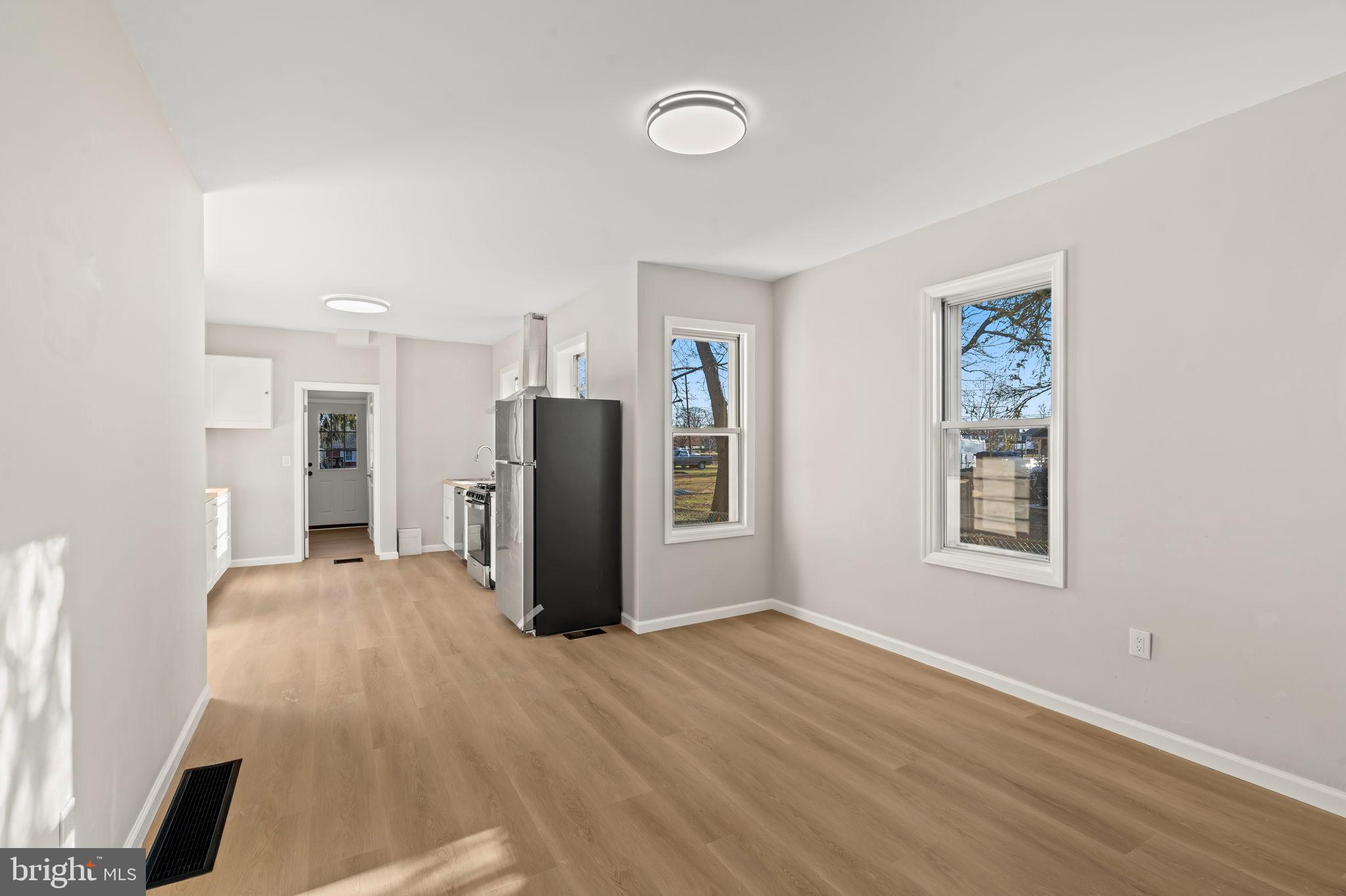 606 Spruce Street Delanco, NJ 08075 - Photo 7 of 29 a view of a refrigerator in kitchen and an empty room with wooden floor and windows