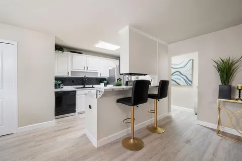 a kitchen with stainless steel appliances kitchen island granite countertop a stove a sink and a white cabinets