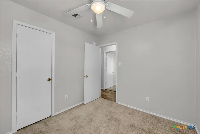 a view of an empty room and a chandelier fan