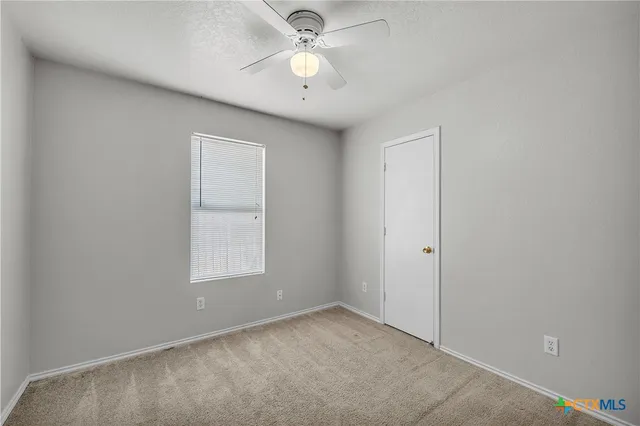 an empty room with a window and a fan
