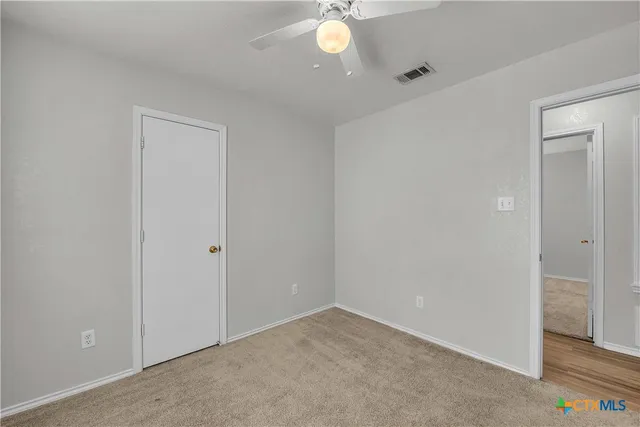 a view of an empty room with a chandelier fan