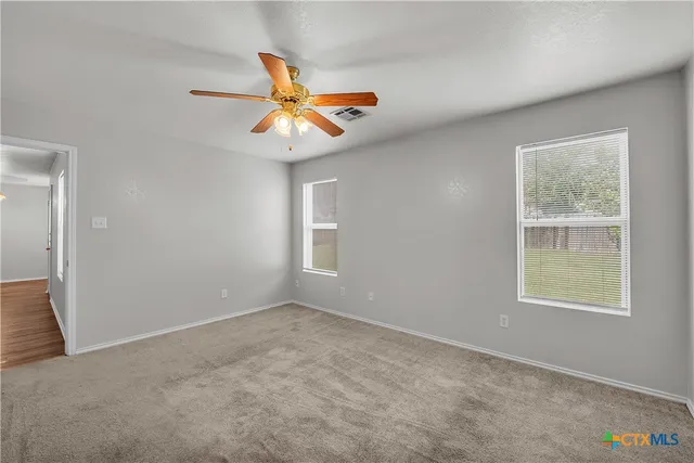 an empty room with windows and fan