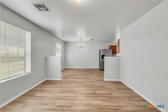 a view of empty room with wooden floor and window