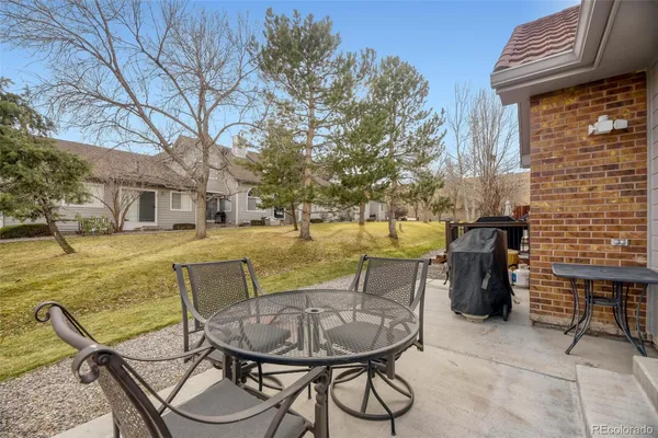 a view of a backyard with table and chairs potted plants and a large tree