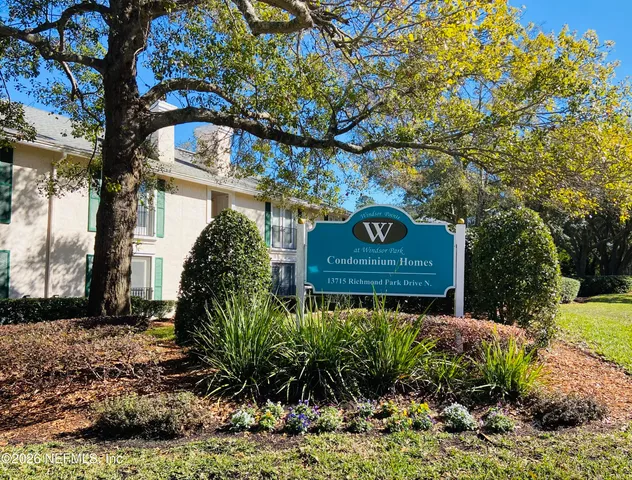 a sign board with a house in the background