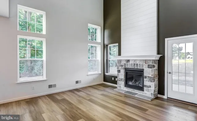 an empty room with wooden floor fireplace and windows