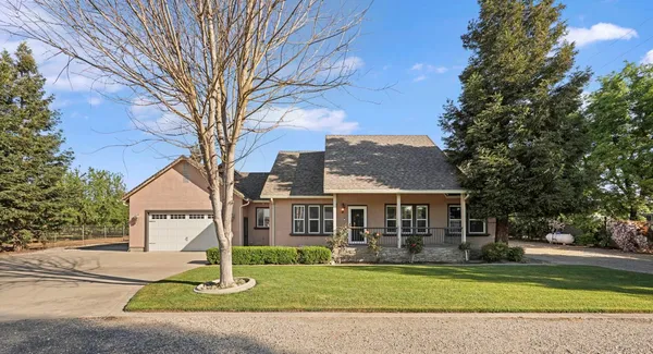 a front view of a house with a garden and trees