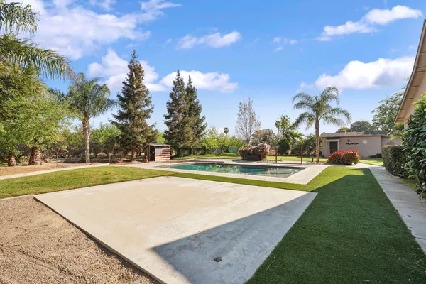 a view of swimming pool with outdoor seating and trees in the background