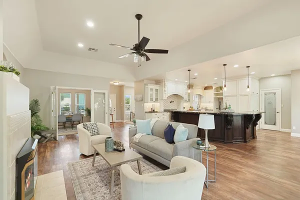a living room with furniture kitchen view and a chandelier