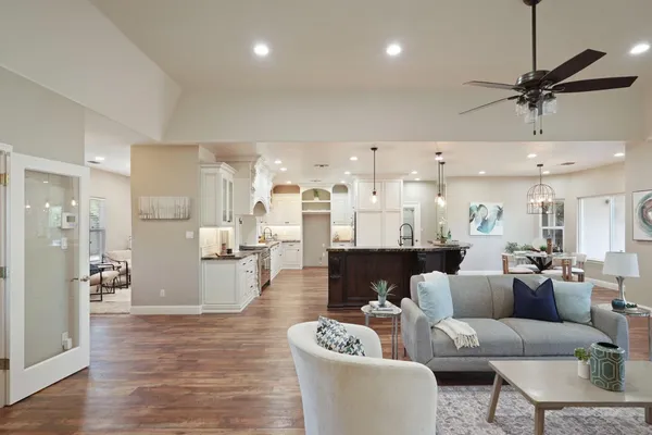a living room with furniture kitchen view and a wooden floor