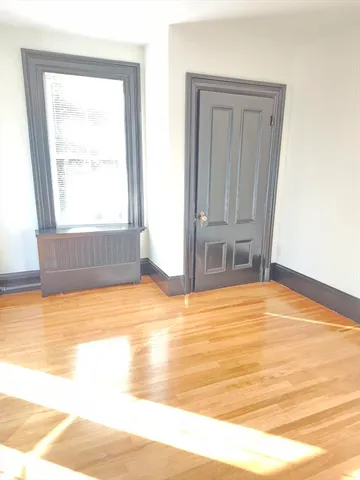 a view of empty room with window and wooden floor