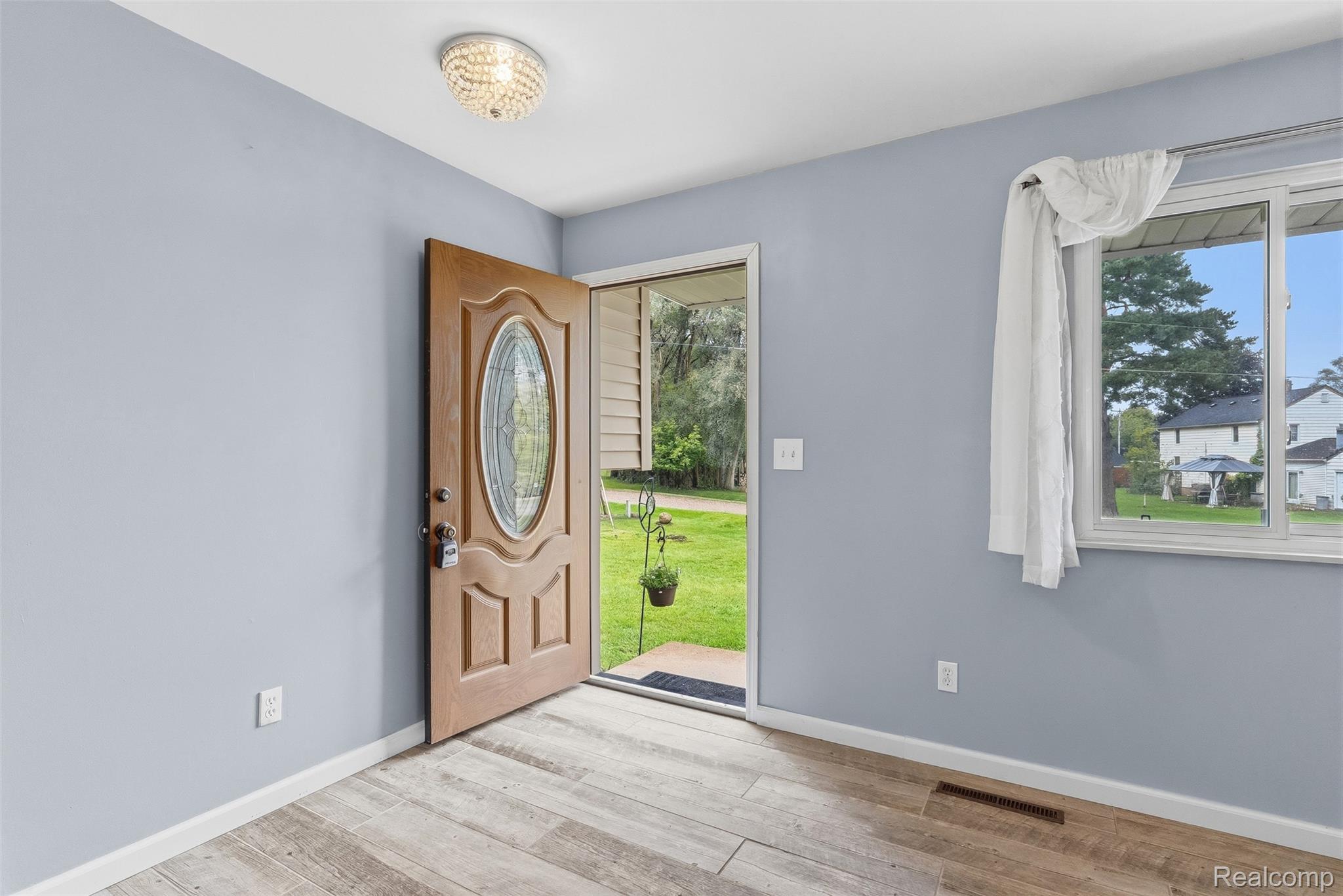 819 Alpine Trail Fenton, MI 48430 - Photo 5 of 41 Wood-finish flooring, light blue wall paint, and a decorative flush-mount ceiling light