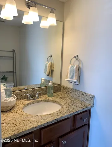 a bathroom with a granite countertop sink and a mirror