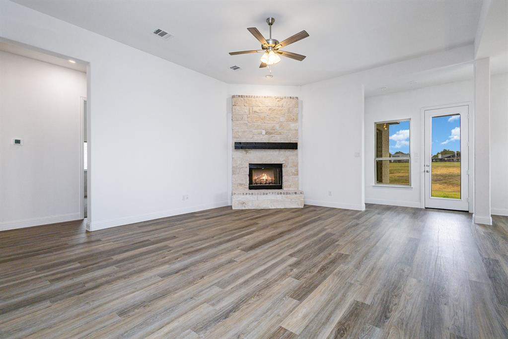 6044 Mango Drive Sanger, TX 76266 - Photo 12 of 27 an empty room with wooden floor fireplace and windows