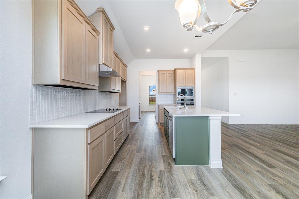 6044 Mango Drive Sanger, TX 76266 - Photo 22 of 27 a kitchen with kitchen island granite countertop wooden floors and a view of living room