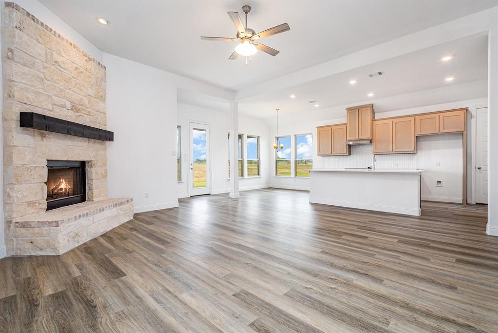 6044 Mango Drive Sanger, TX 76266 - Photo 3 of 27 a view of an empty room and kitchen with fireplace wooden floor