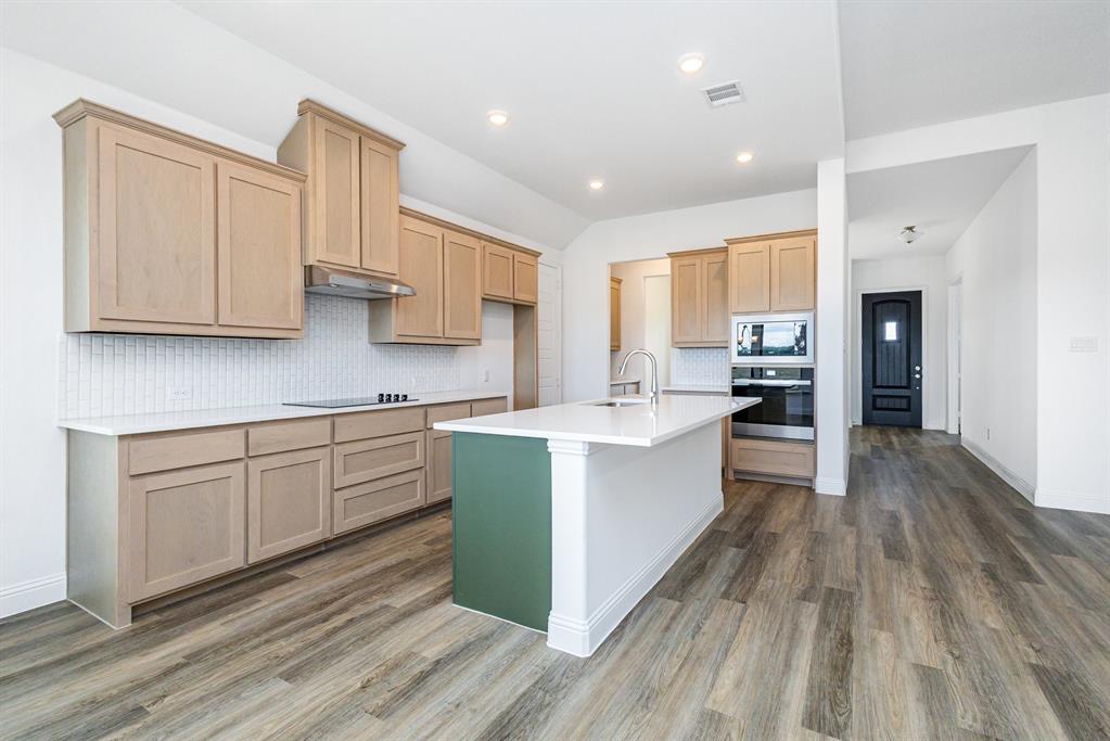 6044 Mango Drive Sanger, TX 76266 - Photo 10 of 27 a large kitchen with stainless steel appliances granite countertop a lot of counter space and wooden floors