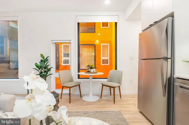 a living room with a table chair and a refrigerator