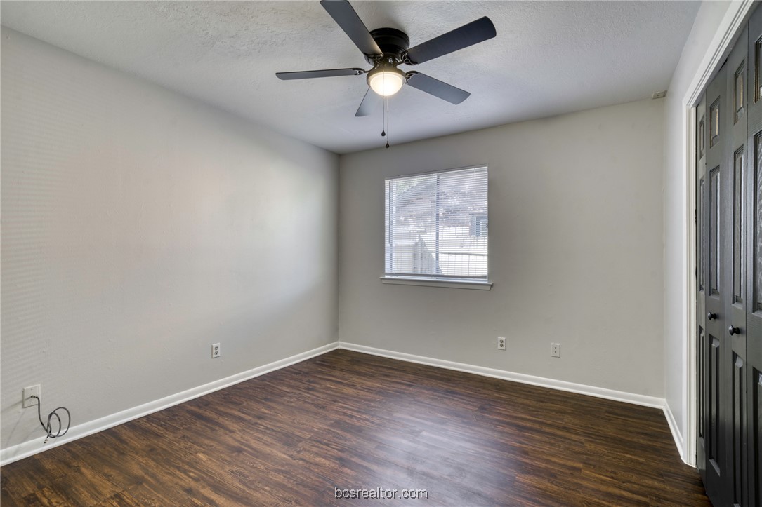 1203 Spring Loop, Unit A College Station, TX 77840 - Photo 11 of 13 Unfurnished room with dark wood-type flooring, a textured ceiling, and ceiling fan