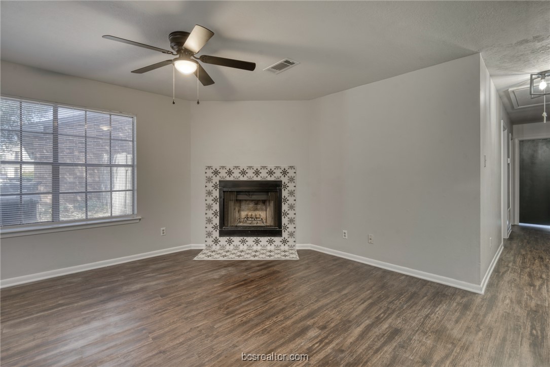 1203 Spring Loop, Unit A College Station, TX 77840 - Photo 3 of 13 Unfurnished living room featuring ceiling fan, dark hardwood / wood-style flooring, and a tile fireplace