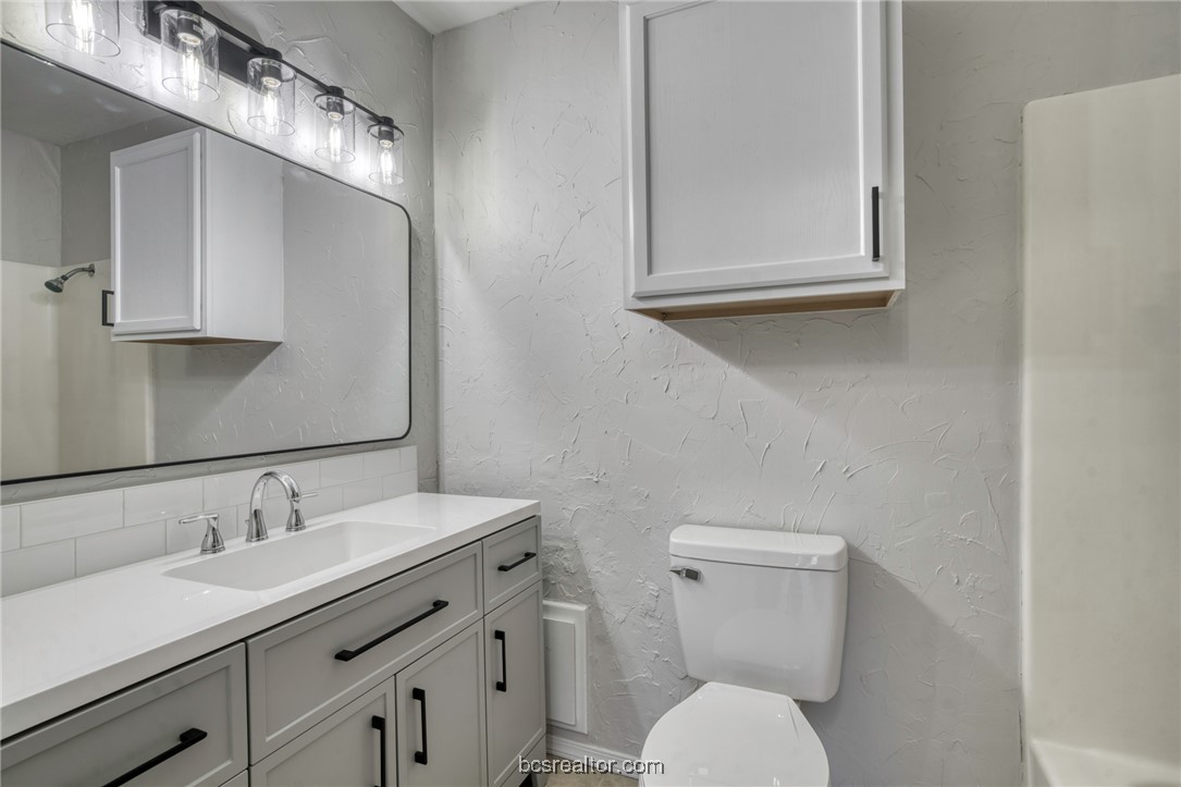 1203 Spring Loop, Unit A College Station, TX 77840 - Photo 8 of 13 Bathroom with toilet, vanity, and backsplash