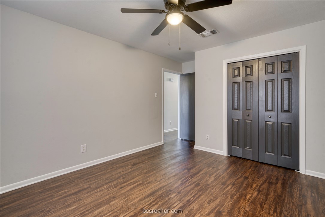 1203 Spring Loop, Unit A College Station, TX 77840 - Photo 9 of 13 Unfurnished bedroom featuring a closet, dark wood-type flooring, and ceiling fan