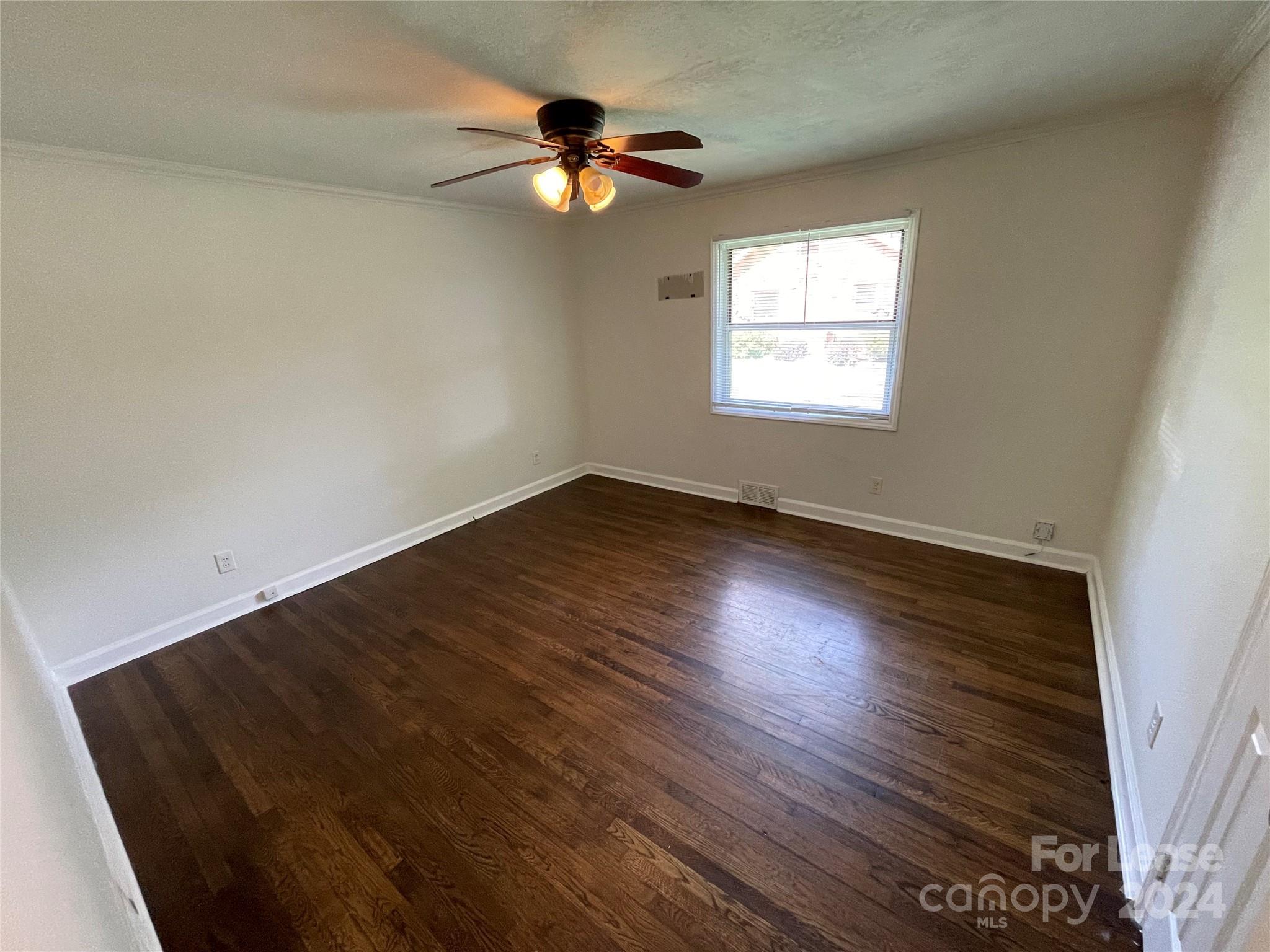 7228 Tuckaseegee Road, Unit A Charlotte, NC 28214 - Photo 4 of 7 an empty room with wooden floor fan and windows