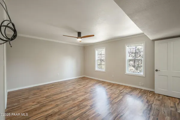 a view of empty room with wooden floor and fan