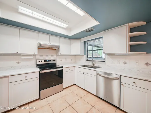 a kitchen with white cabinets appliances and a window