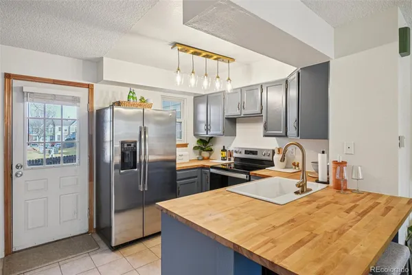 a kitchen with stainless steel appliances kitchen island granite countertop a refrigerator a sink a stove with wooden cabinets