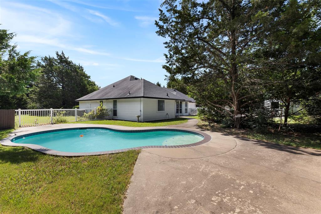 401 Rugged Drive Red Oak, TX 75154 - Photo 32 of 40 Backyard featuring a free-form swimming pool with concrete decking, surrounded by a white picket fence and mature trees