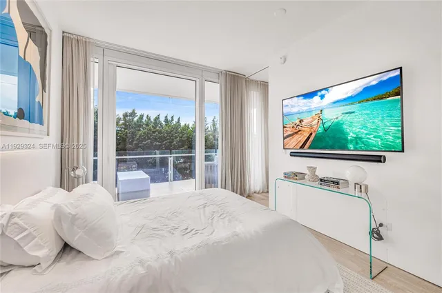 a bedroom with a bed and a flat tv screen next to a window