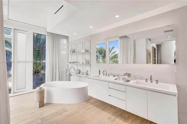 a spacious bathroom with a double vanity sink a mirror and a bathtub