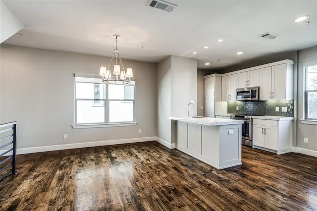 a kitchen with granite countertop a stove a sink and white cabinets with wooden floor