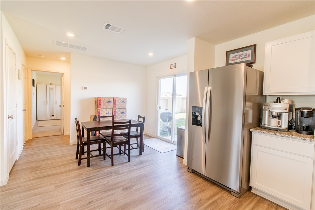 6029 Toby Bend Bryan, TX 77807 - Photo 9 of 25 a kitchen with stainless steel appliances a refrigerator a stove a dining table and chairs with wooden floor