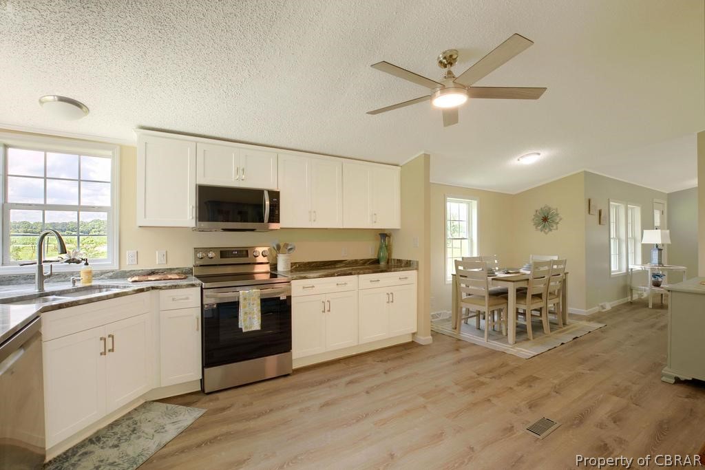 1626 Buckley Hall Road Dutton, VA 23050 - Photo 10 of 37 a kitchen with stainless steel appliances granite countertop a stove top oven a sink a dining table and chairs with wooden floor