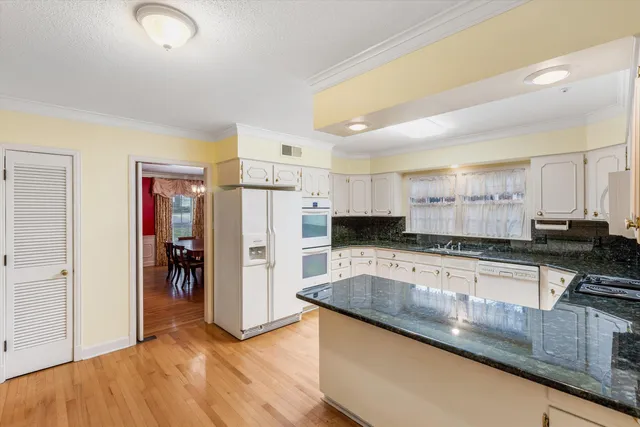 a kitchen with stainless steel appliances granite countertop a refrigerator a stove and a sink with wooden floor