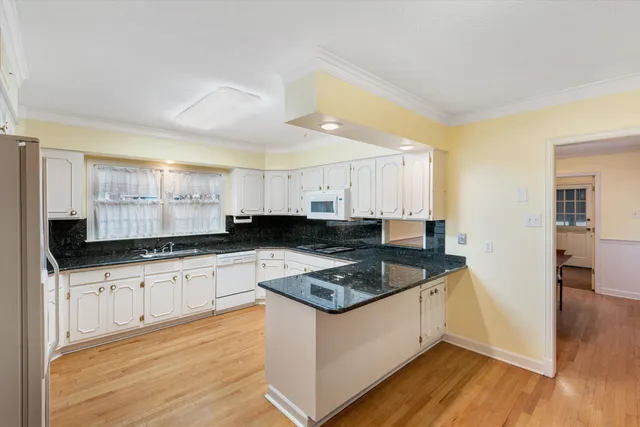 a kitchen with granite countertop a sink a stove top oven and cabinetry