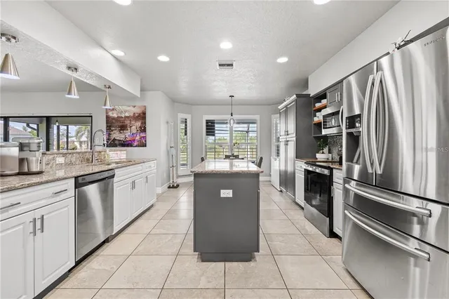 a kitchen with stainless steel appliances kitchen island granite countertop a table chairs in it and wooden floors