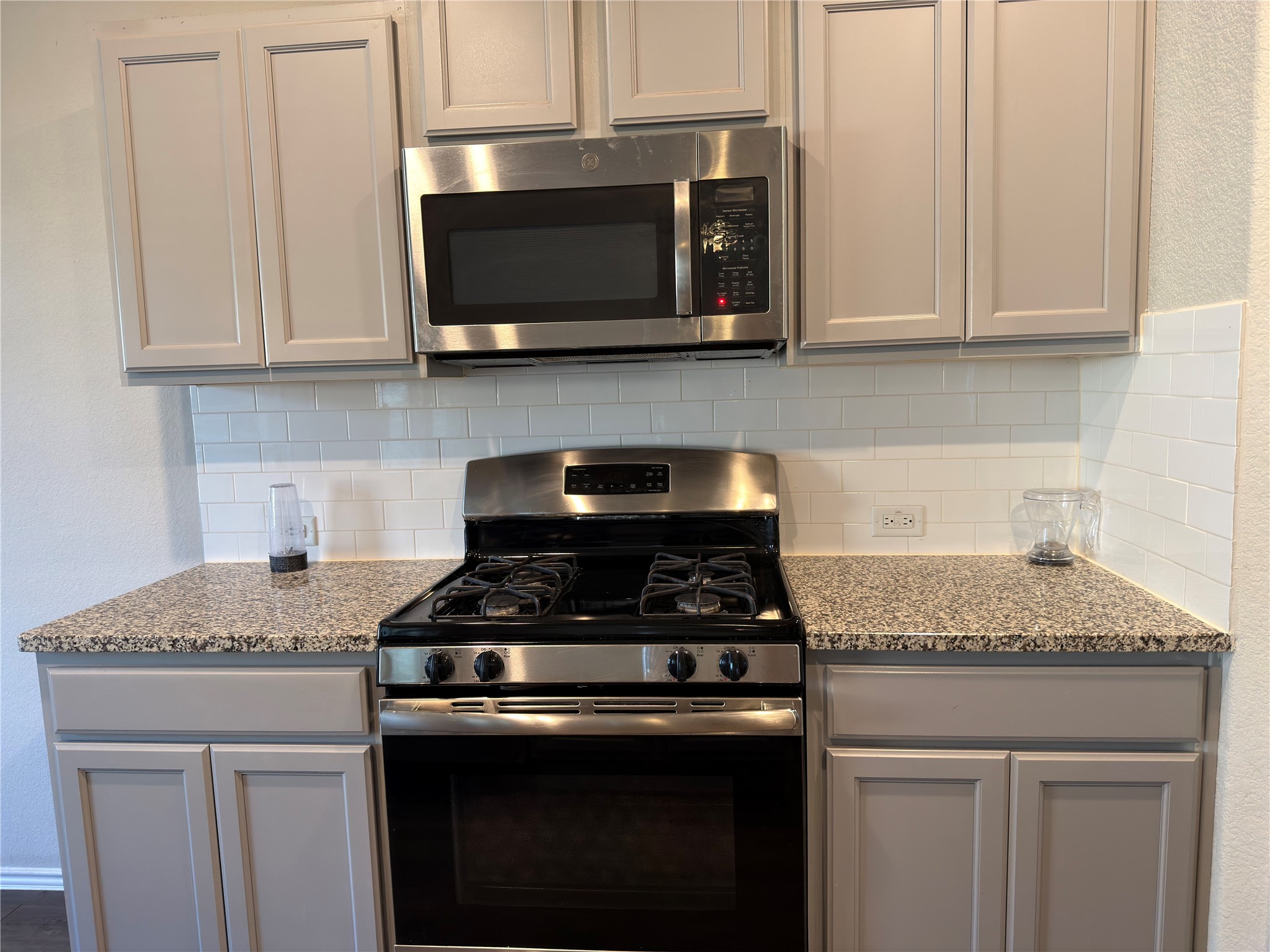 21700 Urraca Lane Pflugerville, TX 78660 - Photo 6 of 40 Kitchen featuring appliances with stainless steel finishes, light stone countertops, gray cabinetry, and decorative backsplash